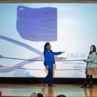 TaRita Johnson points to a person holding a rope with two others on stage